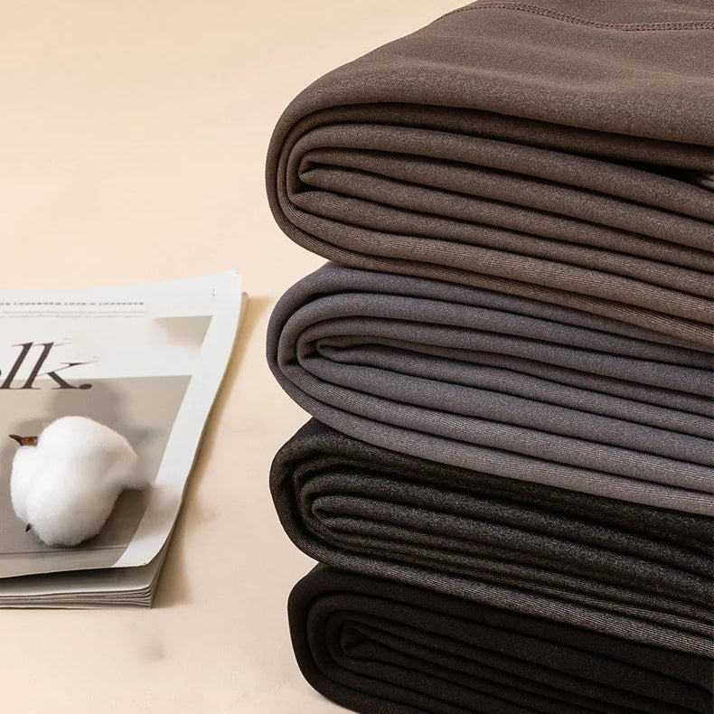 Stack of folded gray blankets on a beige surface with a magazine underneath.