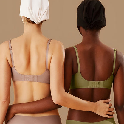 Two women wearing sports bras and leggings against a beige background