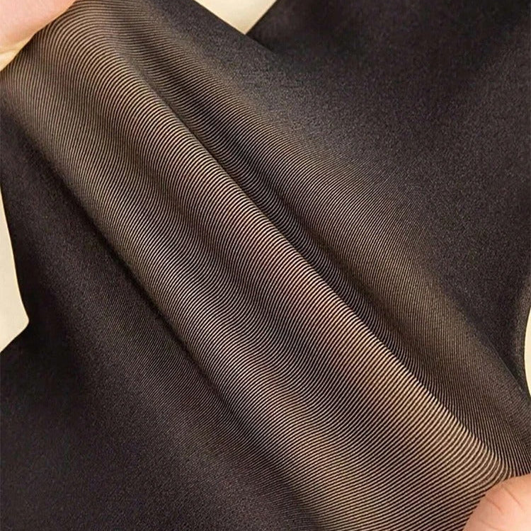 Close-up of brown fabric with a subtle pattern held by hands.